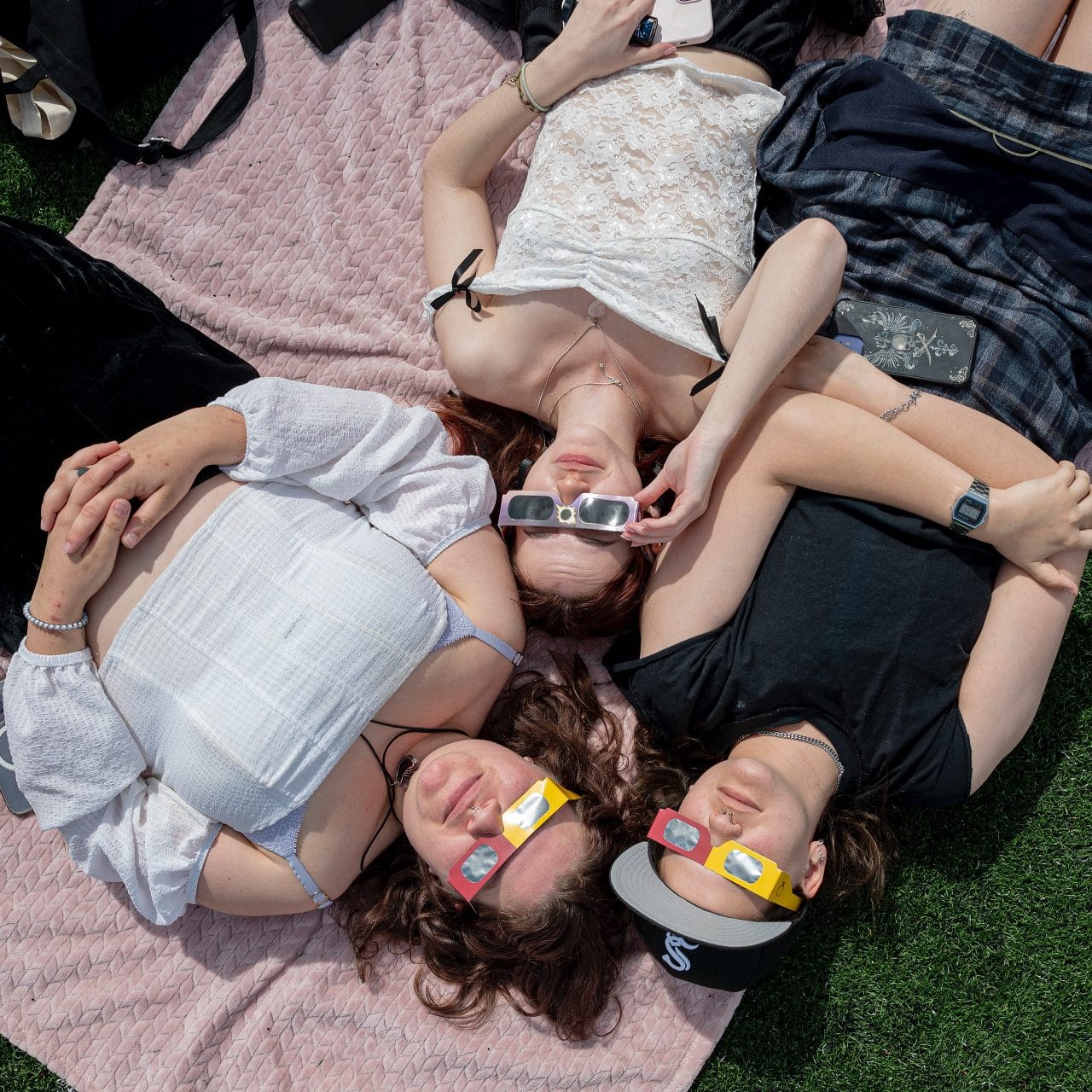 Students lying on picnic blankets in eclipse glasses, April 2024