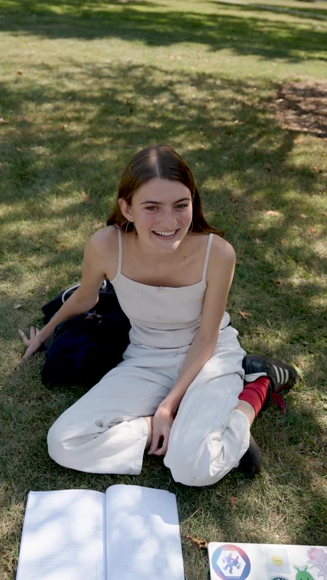Reel cover: a student sitting on the grass with a notebook