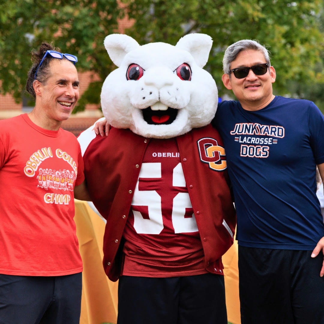 Two people posing with an Oberlin mascot outdoors