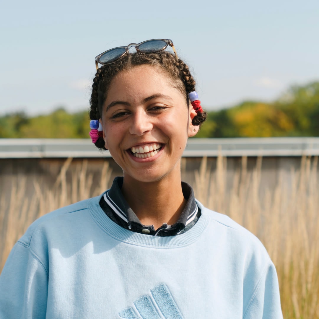 Outdoor portrait of a smiling person in a pale blue top