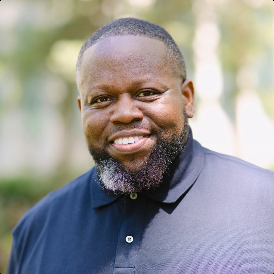 Outdoor portrait of a smiling man in a black polo
